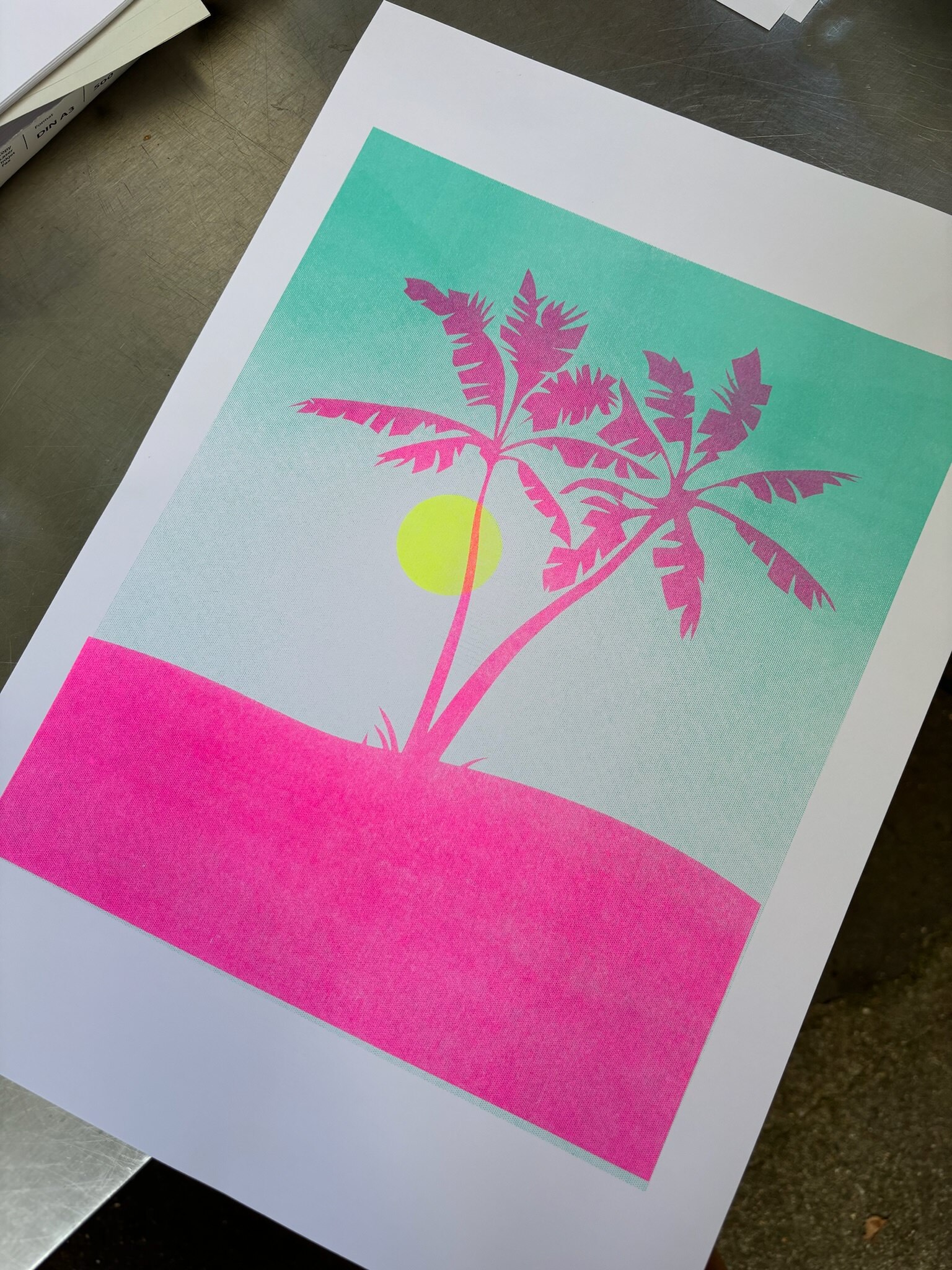 Photo of a poster with a beach, palm tree + sun motive printed in neon colors