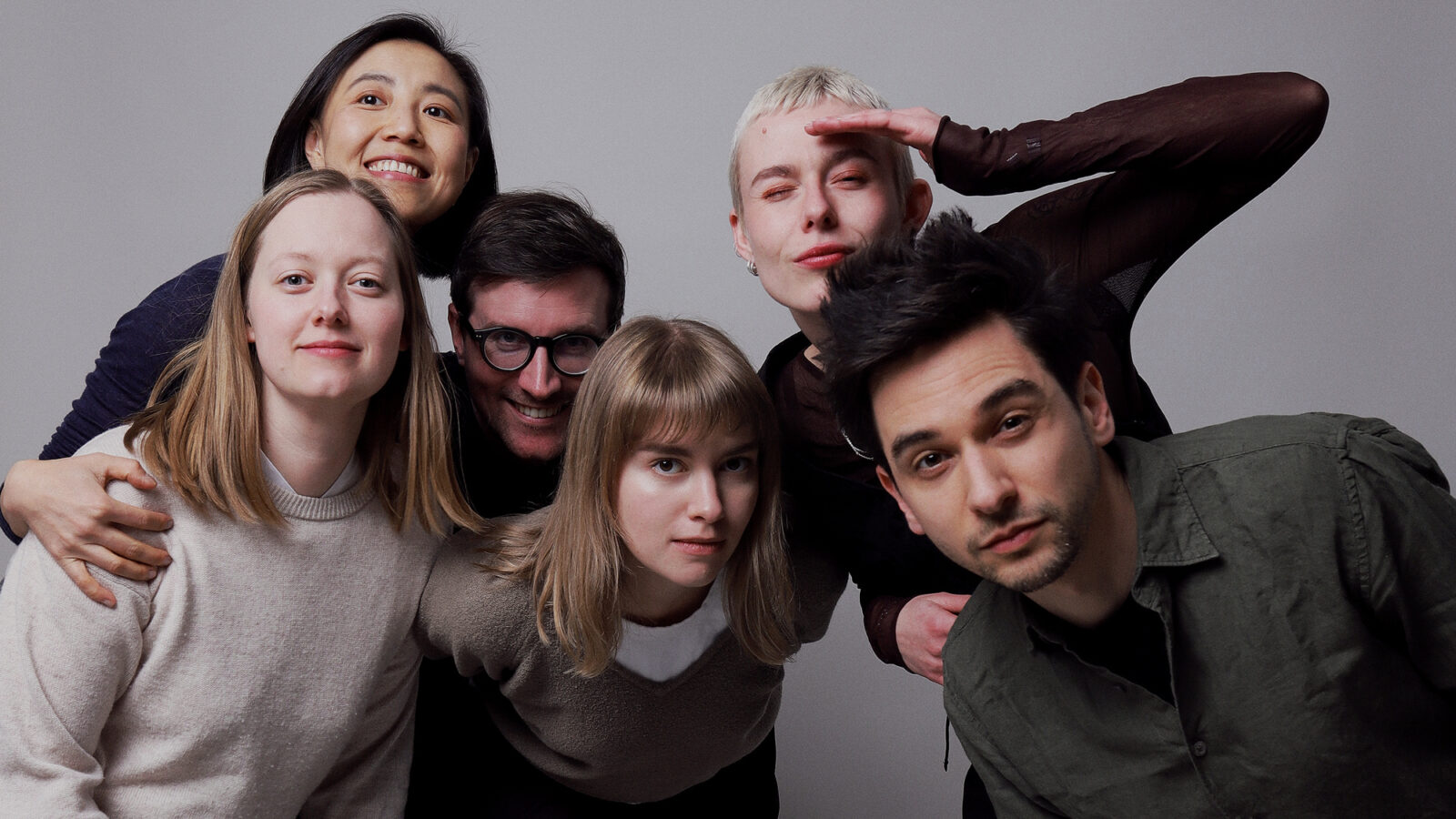 Photo of the entire Village One team, with six people standing close to each other, smiling, hugging and looking skeptically into the camera