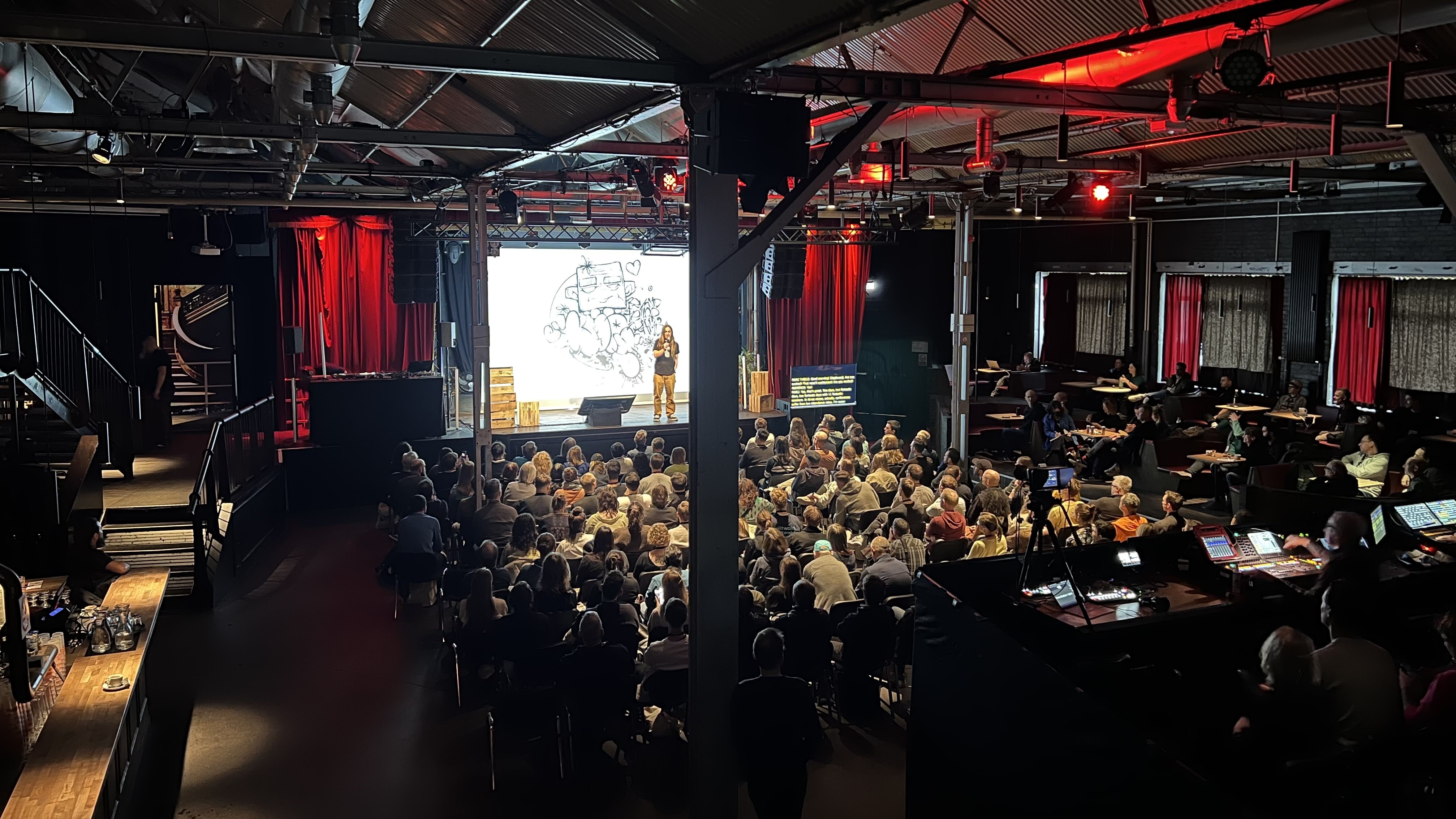 Photo of a conference stage with the Beyond Tellerrand organizer Marc Thiele on stage and many people in the audience