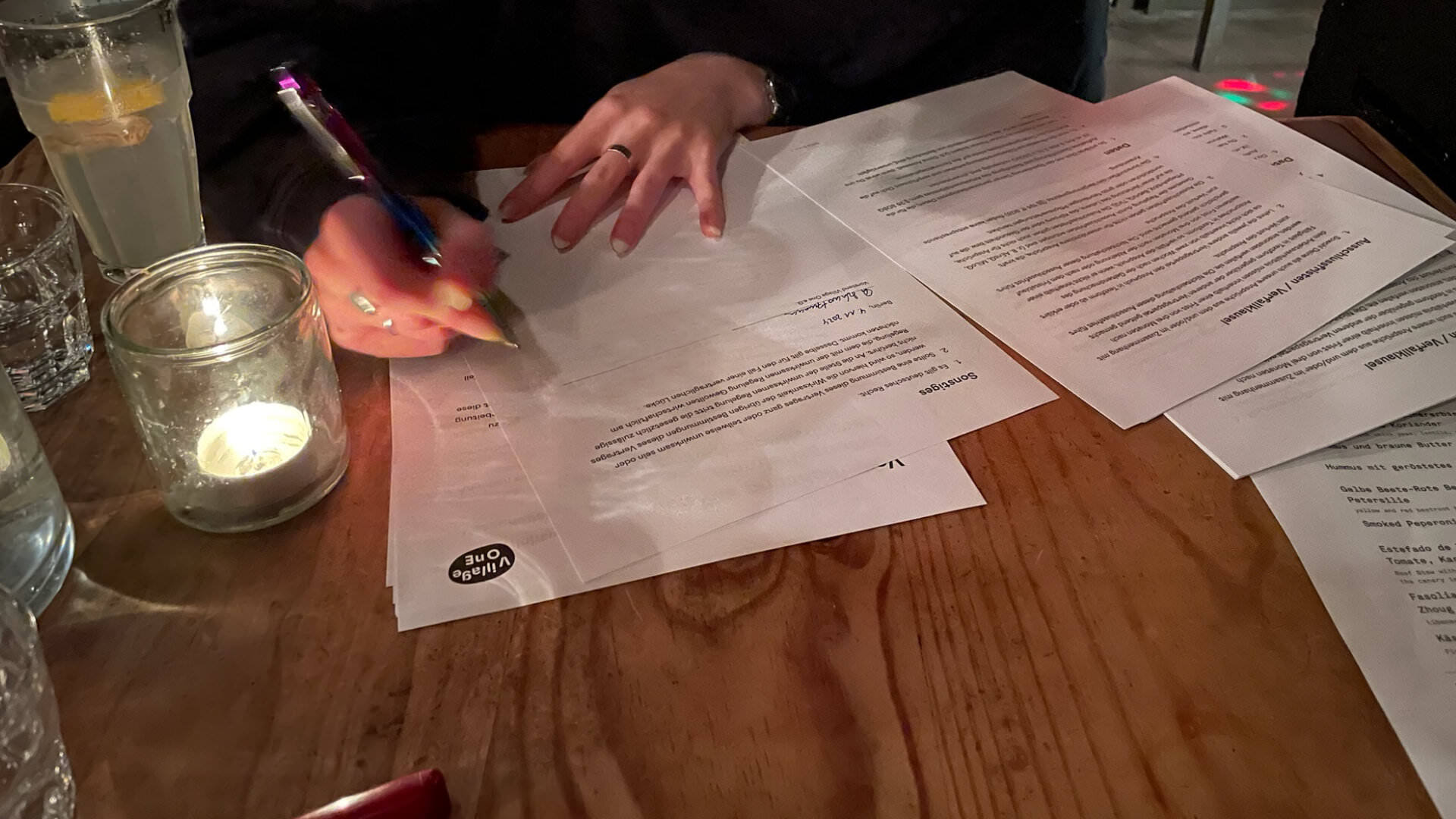 Photo of someone sitting across the table at a bar, signing a working contract