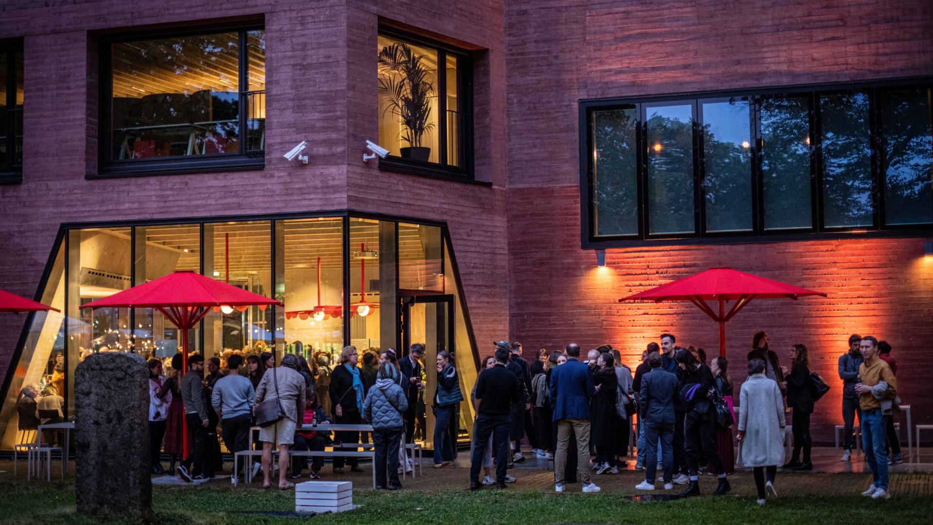 A photo from the Publix opening, shot from the back yard towards the building, at dusk, large group of people mingling and chatting inside and outside